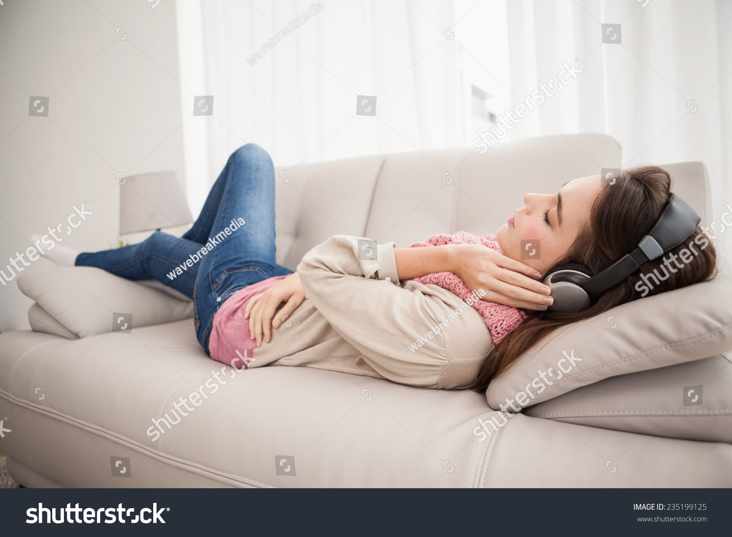 Pretty Brunette Listening To Music On The Couch At Home In The Living