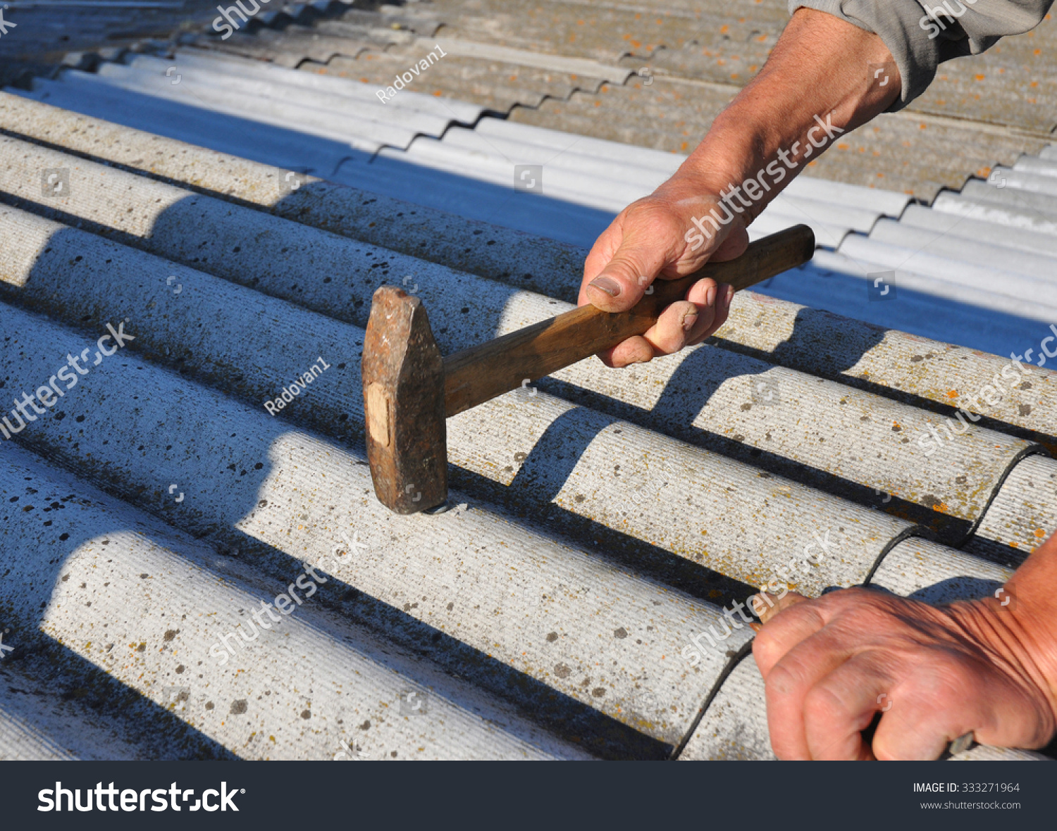 Roofer Hammering Nail In Asbestos Old Roof Tiles. Roofing Construction