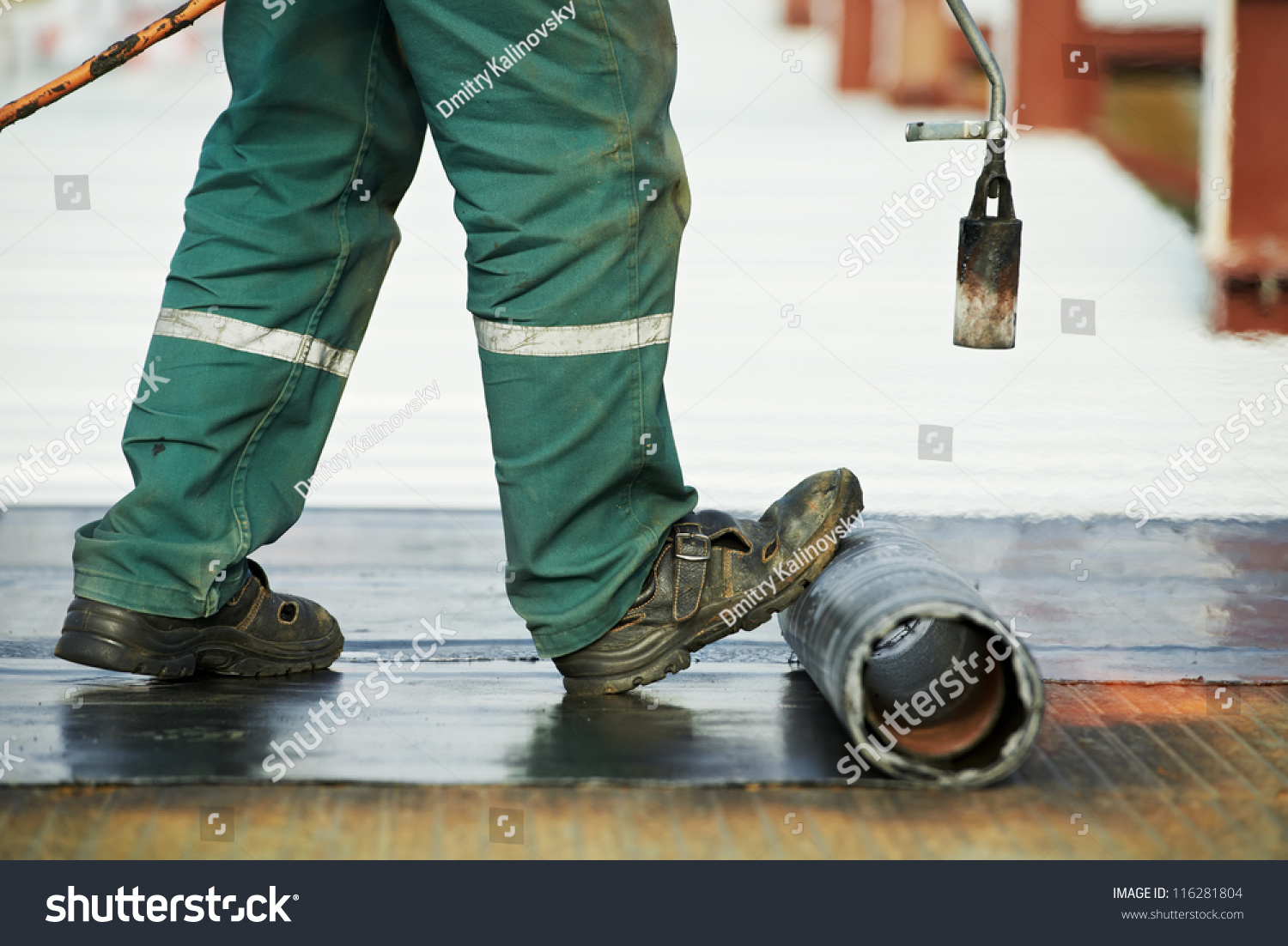 Roofer Installing Roofing Felt With Heating And Melting Of Bitumen Roll By Torch On Flame During