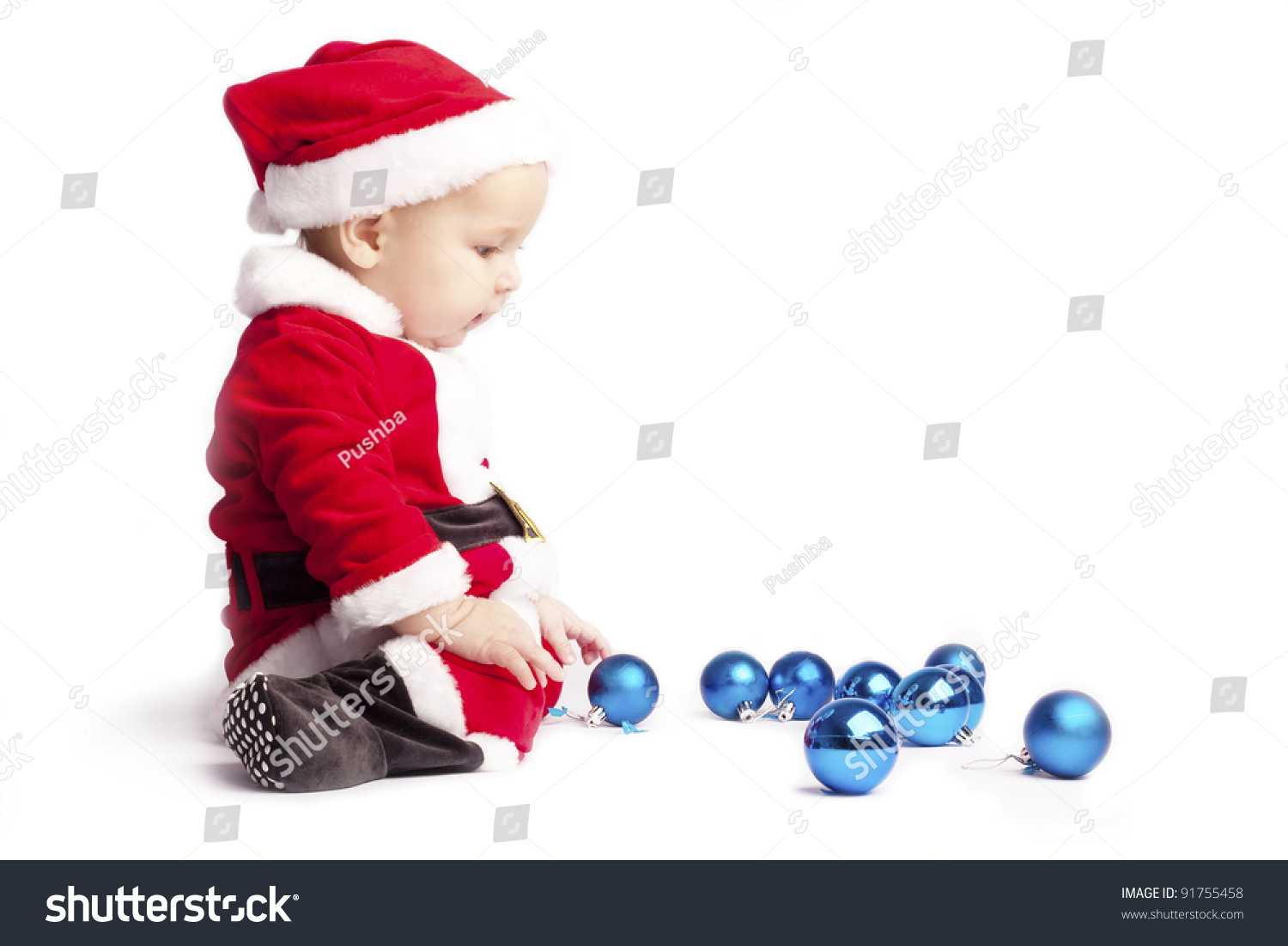 Sad Little Baby Boy Santa Sits And Stares At The Blue Christmas Balls On White Background Put ...