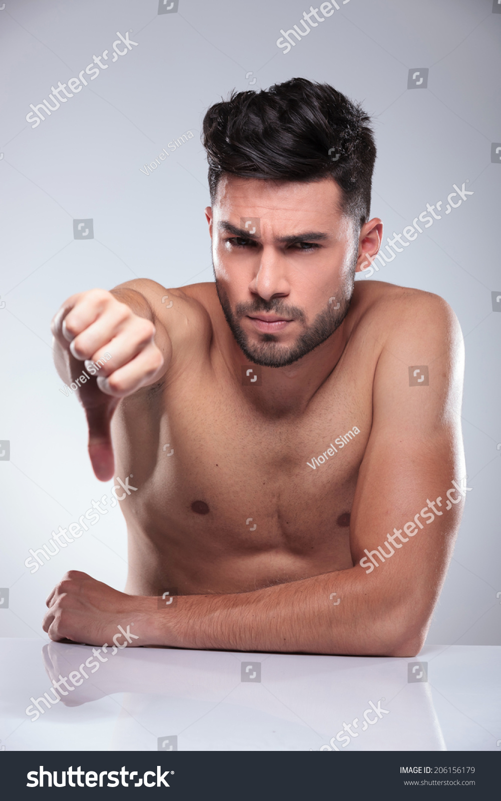 Sad Naked Man Making The Thumbs Down Hand Sign In Studio Stock Photo