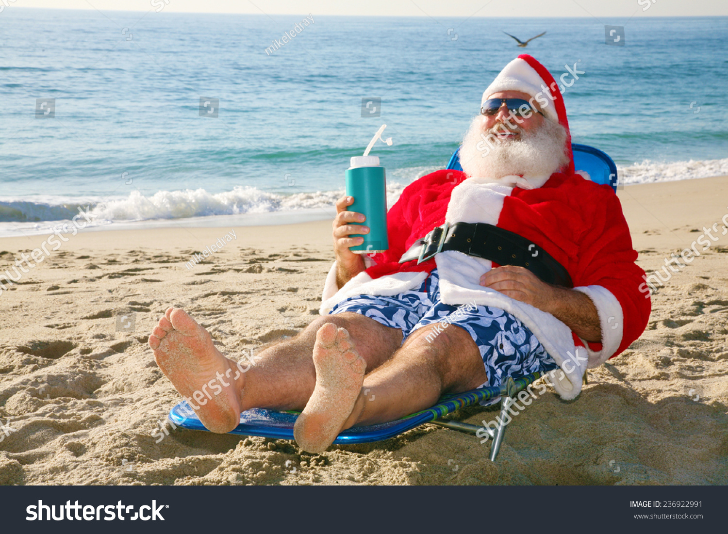 Santa Claus Relaxing In His Lounge Chair On A Tropical Sandy Beach