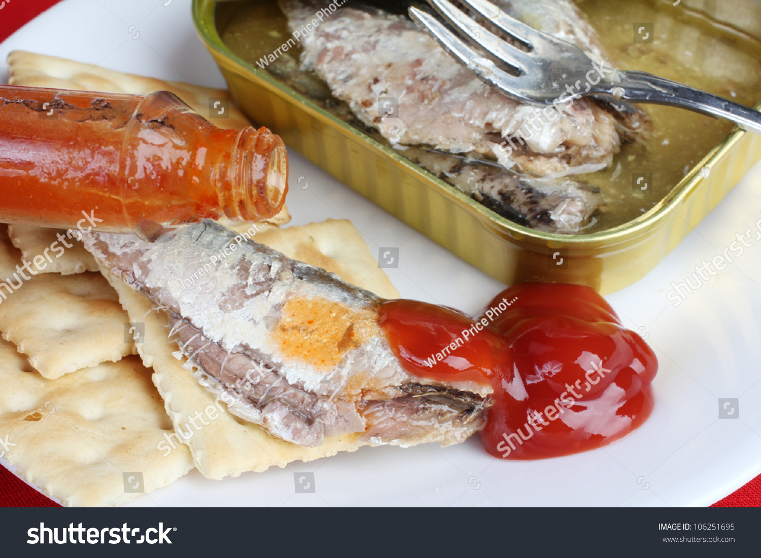 Sardines On Saltine Crackers With Ketchup And Hot Sauce Being Poured 