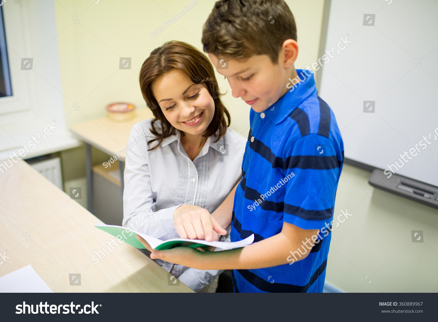 school boy with notebook and teacher in classroom school boy with notebook and teacher in classroom