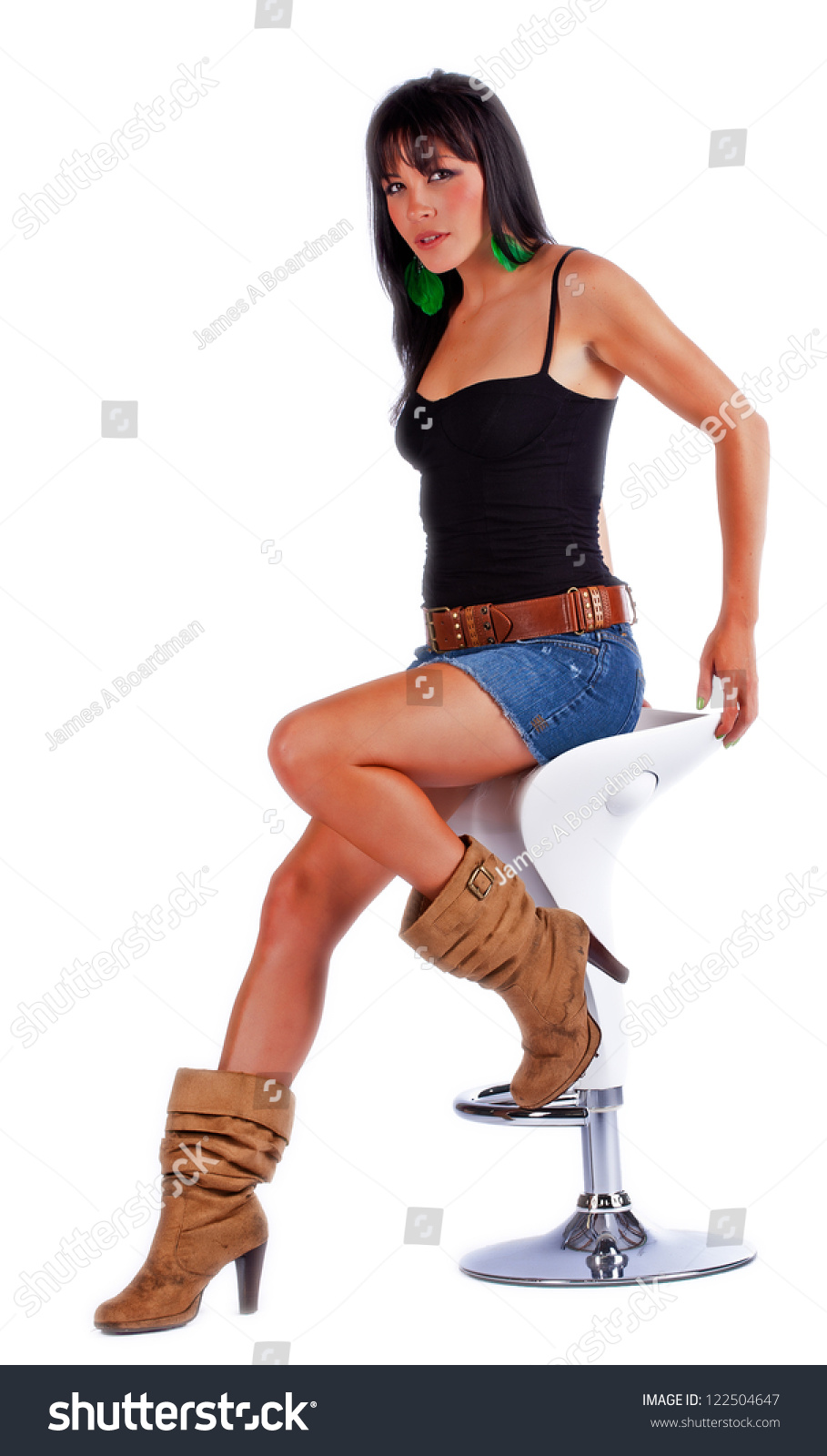 Sexy Woman In Blue Jean Skirt Sitting On A Stool While Isolated On