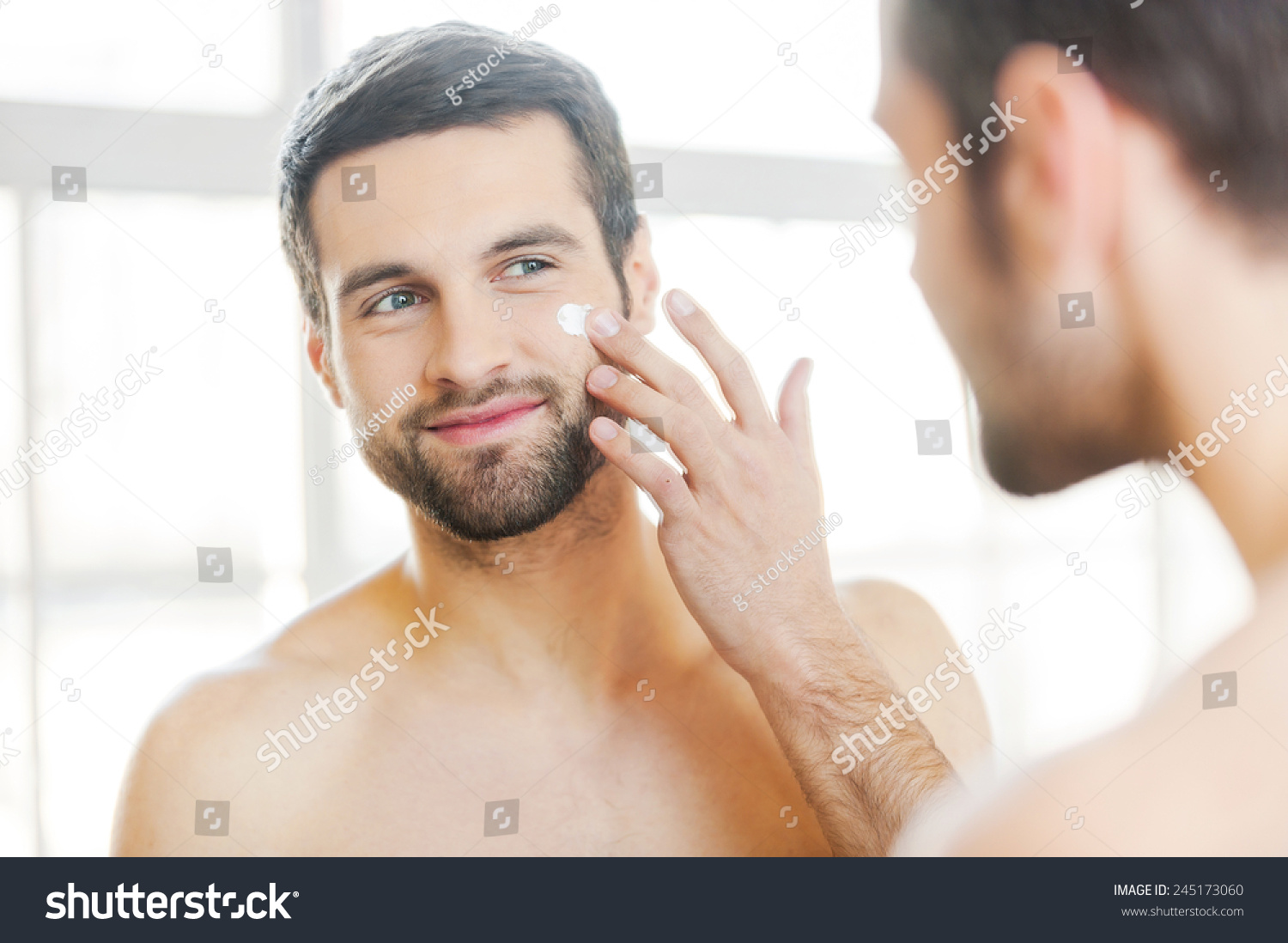 Skin Care Handsome Young Shirtless Man Applying Cream At His Face And