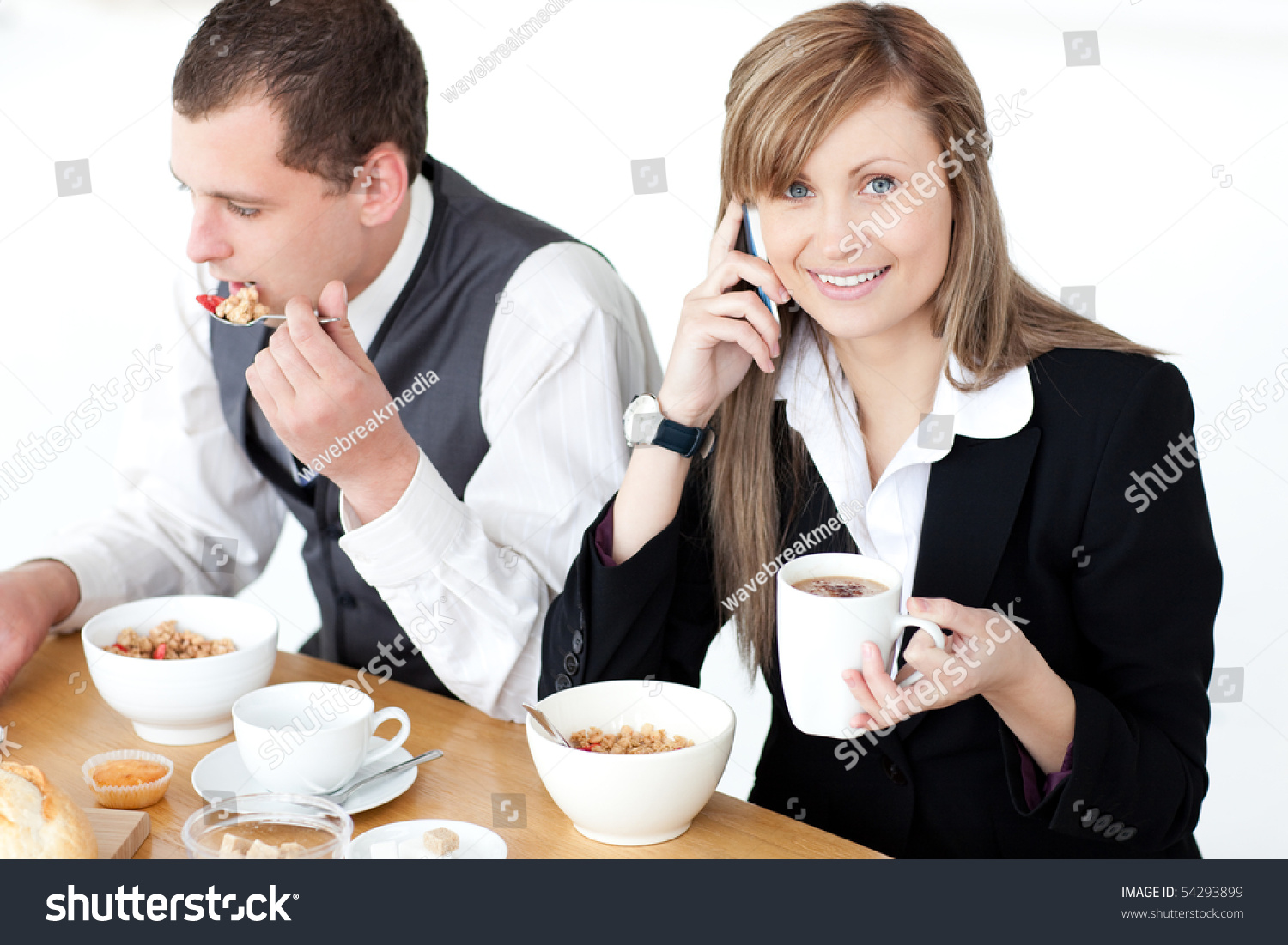Smiling Businesswoman Talking On Phone While Having Breakfast With Her Husband At Home Stock