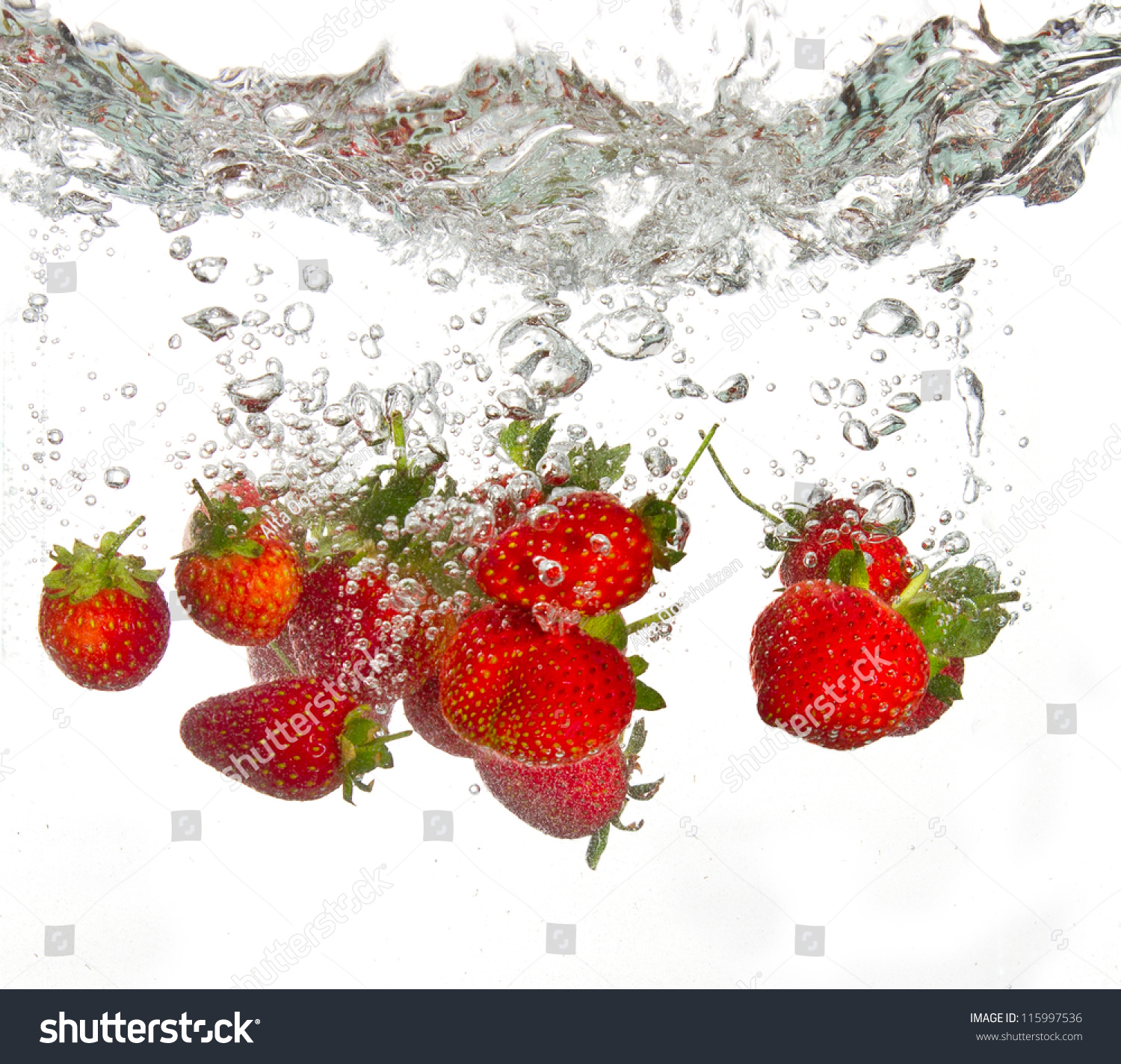 Strawberries Falling Into Water Causing Bubbles All Around It Stock