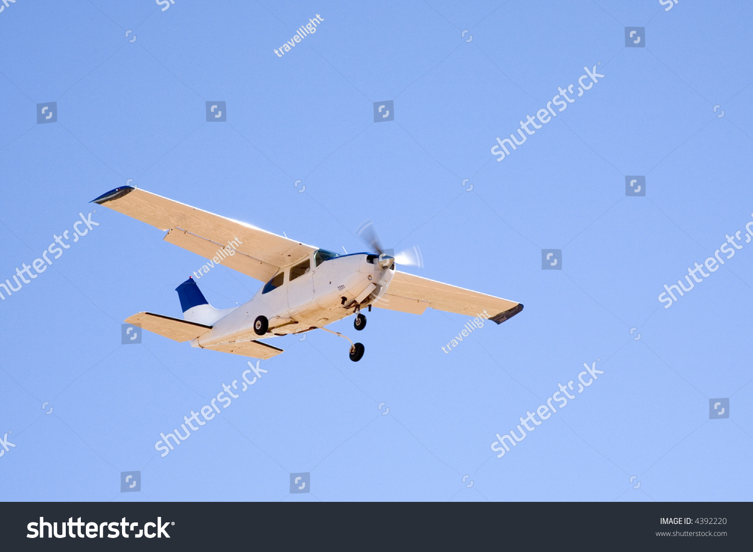Sunlit Cessna Light Aeroplane Flying In Clear Blue Sky. Stock Photo