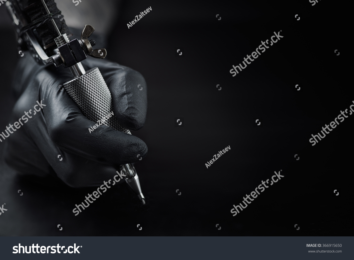 Tattoo artist holding tattoo machine on dark background with space for text Tattoo artist holding tattoo machine on dark background with space for text