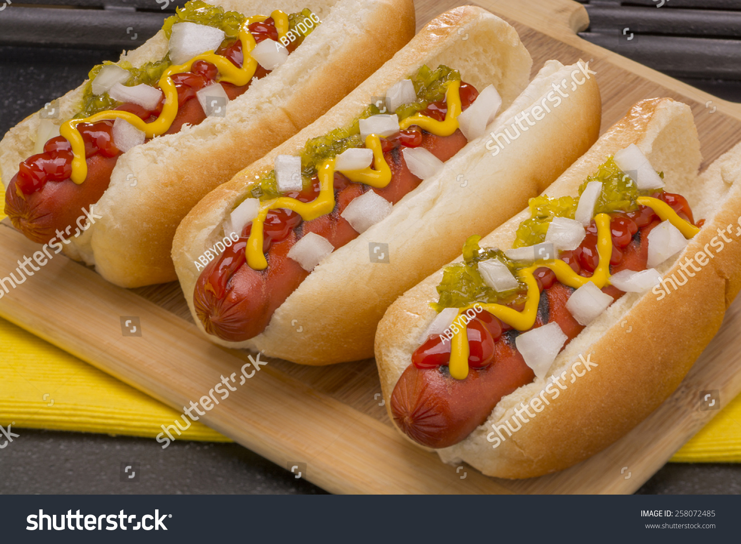 Three Hot Dogs With Mustard Ketchup Pickle Relish And Onions Stock 
