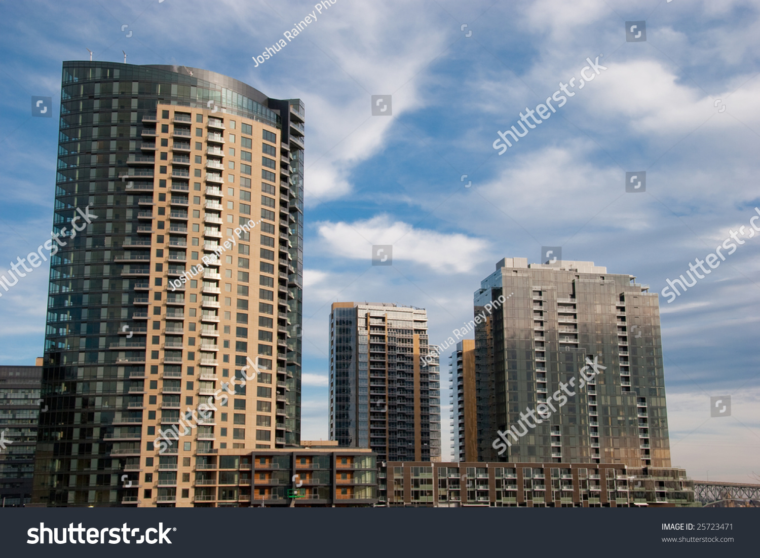 Three Skyrise Condo Buildings With A Blue Sky And Clouds In The