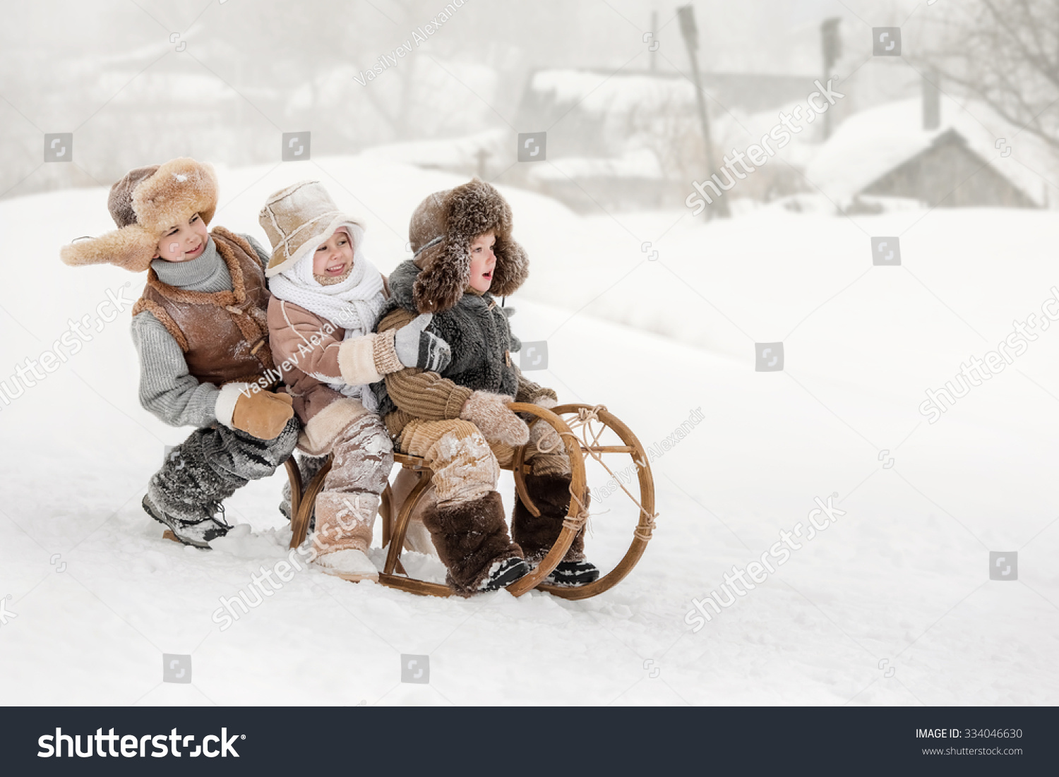 Three small children slide down hills on sleds in winter sunny day Three small children slide down hills on sleds in winter sunny day