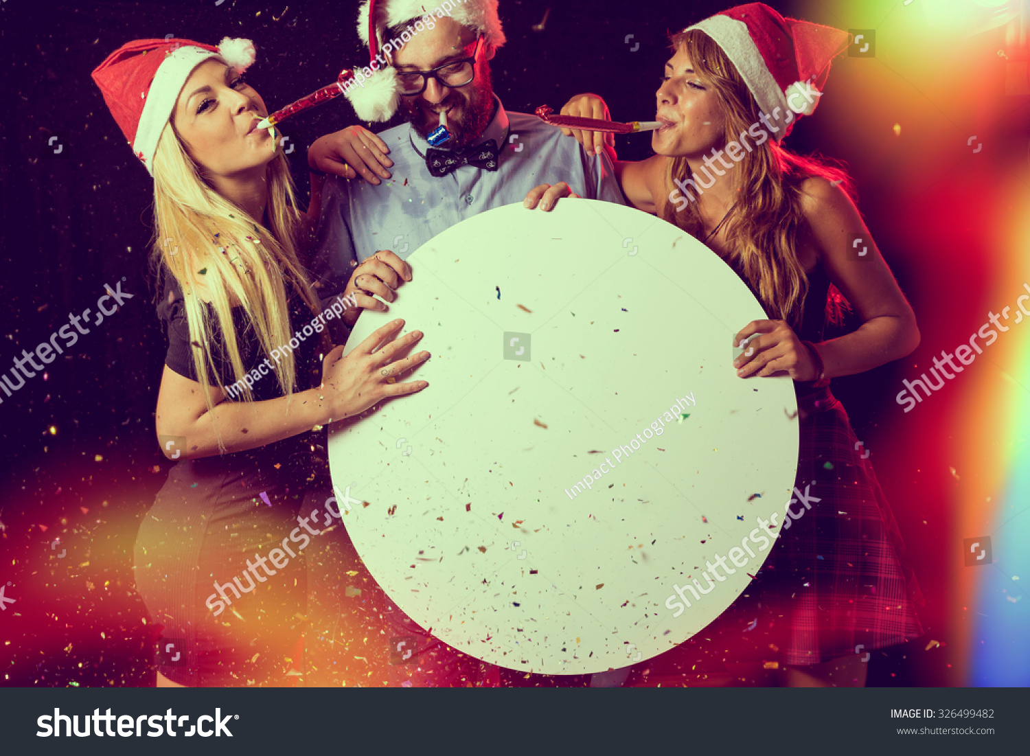 Three Young People Having Fun At New Years Eve Party Blowing