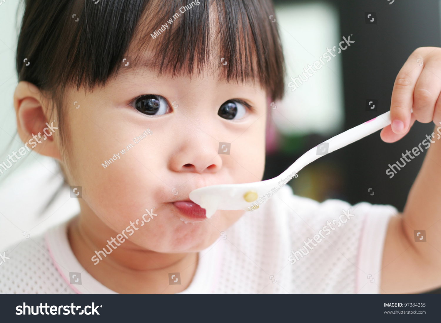 Toddler Girl Feeding Herself With A Spoon Of Porridge Stock Photo