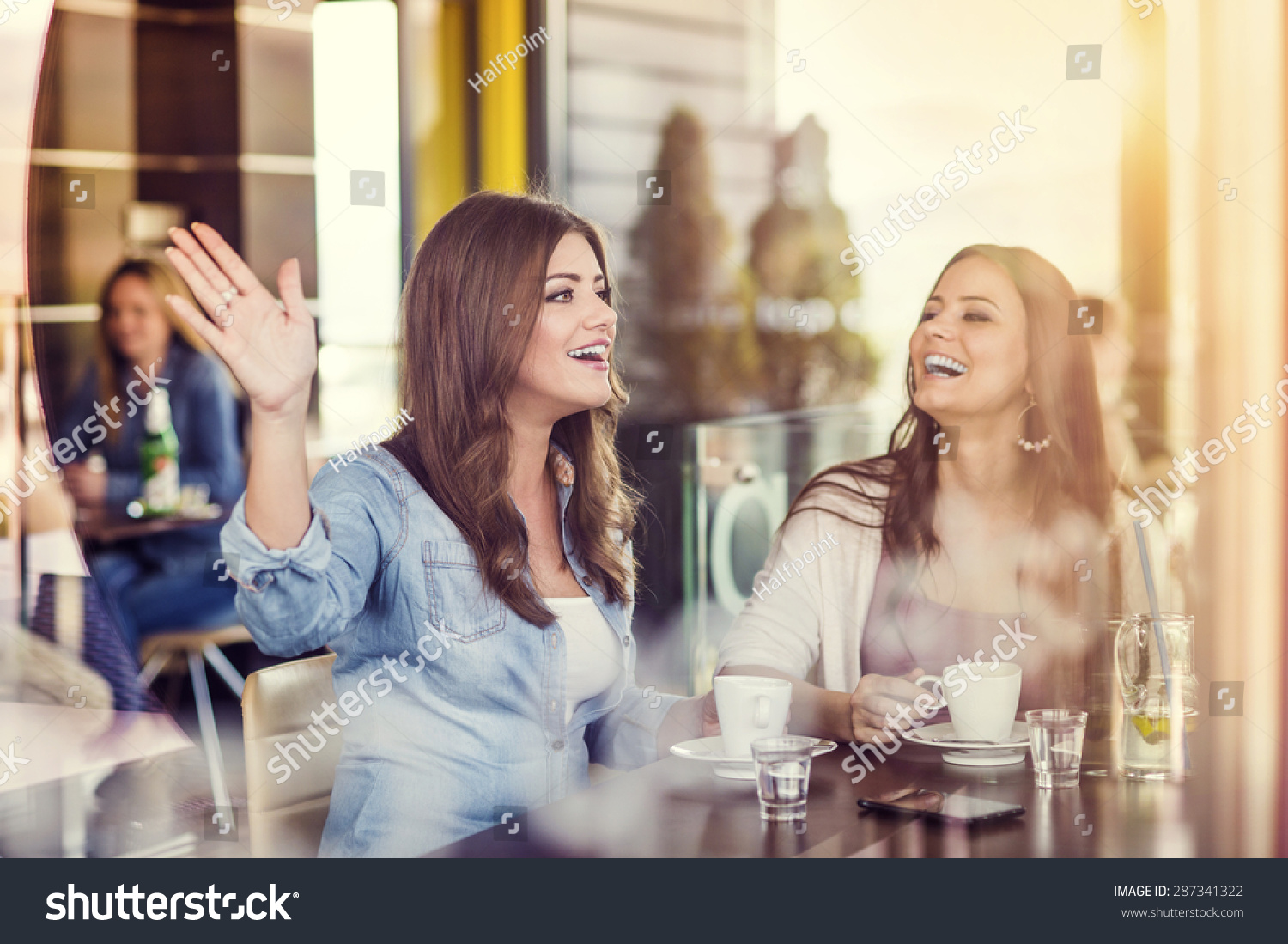 Two beautiful women drinking coffee and chatting in cafe Two beautiful women drinking coffee and chatting in cafe