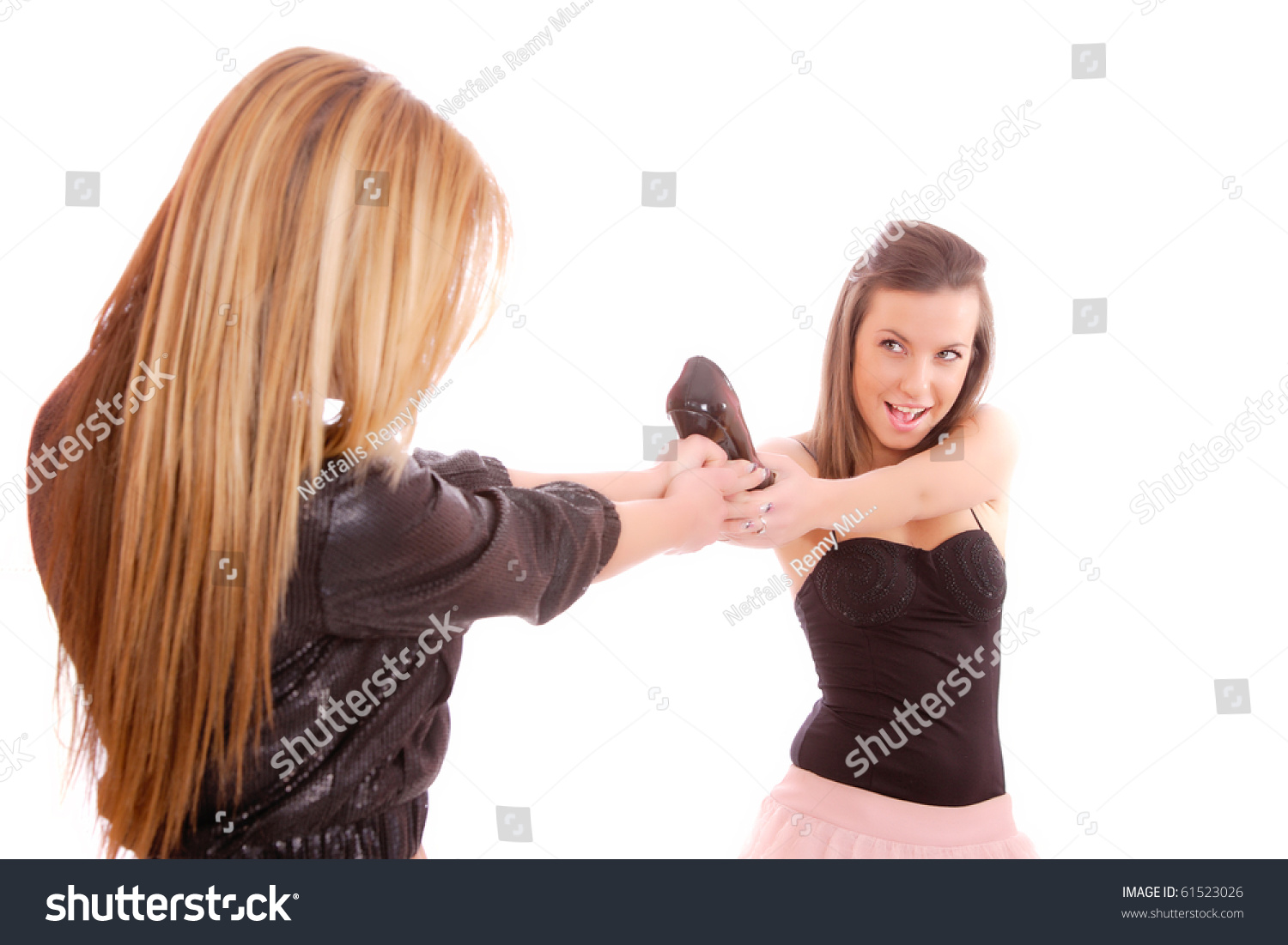 Two Young Woman Fighting For A Shoe Over A White Background Stock Photo