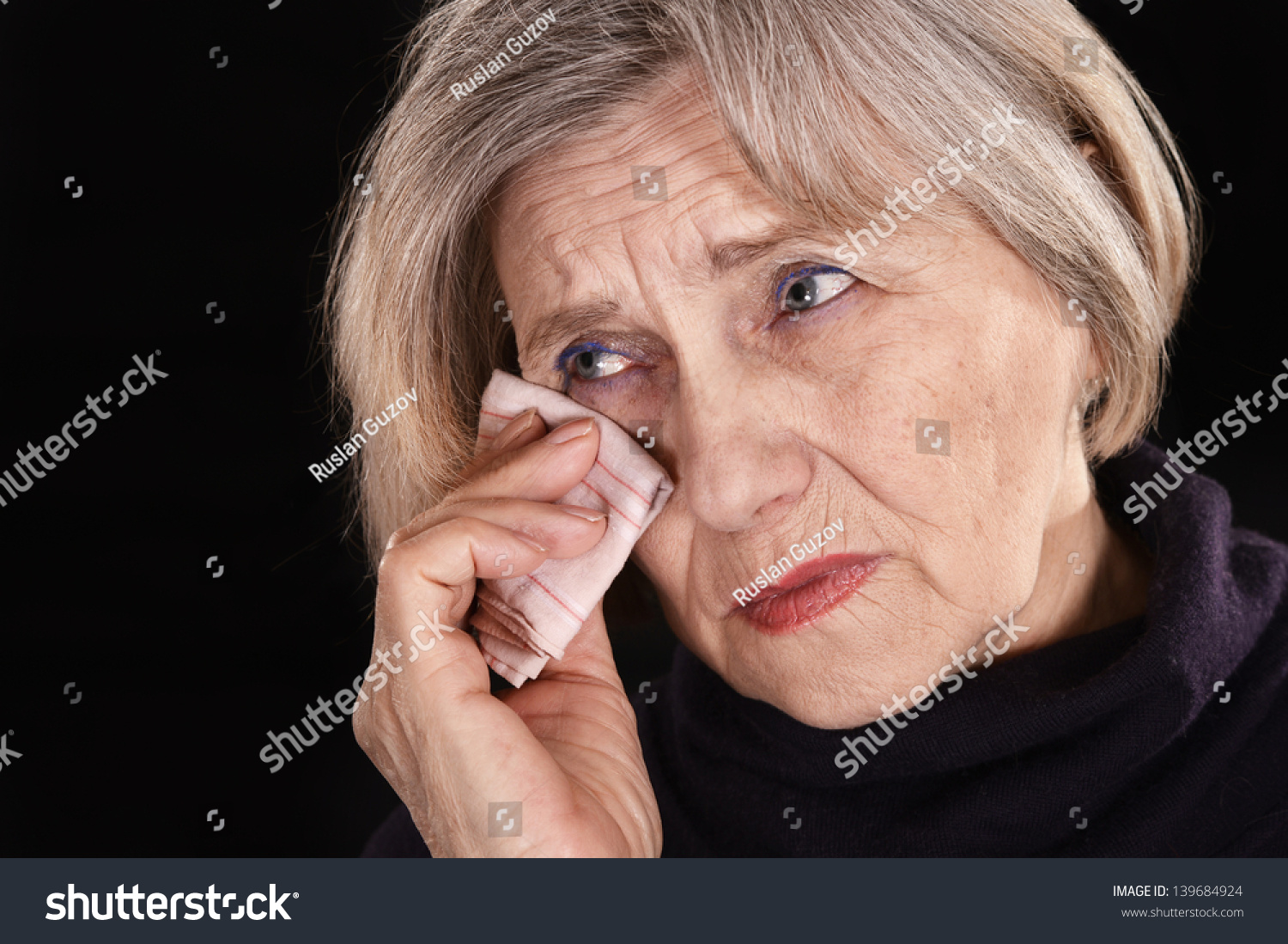 Unhappy senior woman with handkerchief on a black background Unhappy senior woman with handkerchief on a black background