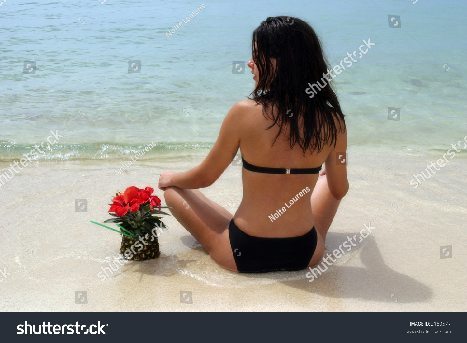 Woman Sitting On Beach Having A Pineapple Drink Staring At The Ocean Stock Photo