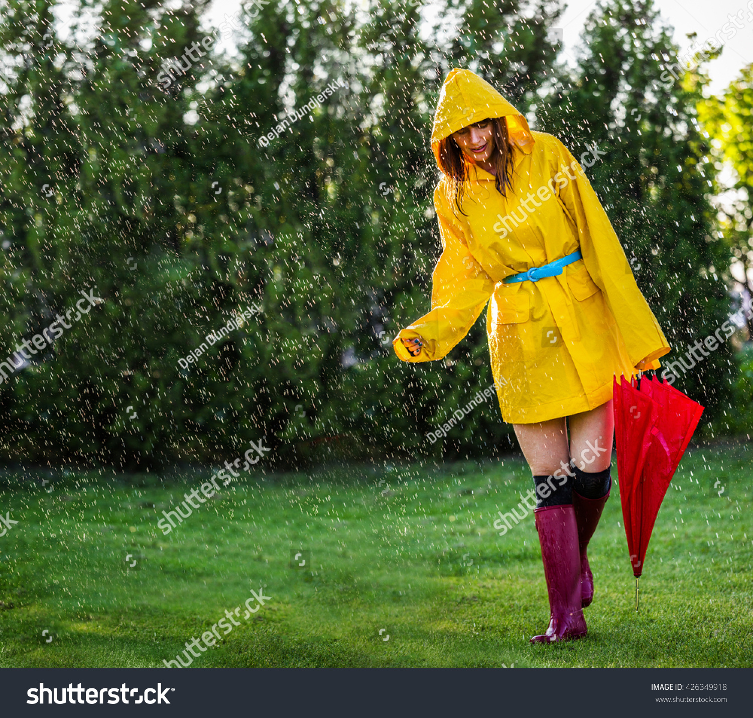 Woman Wearing Yellow Raincoat With Umbrella Out In The Rain Stock Photo