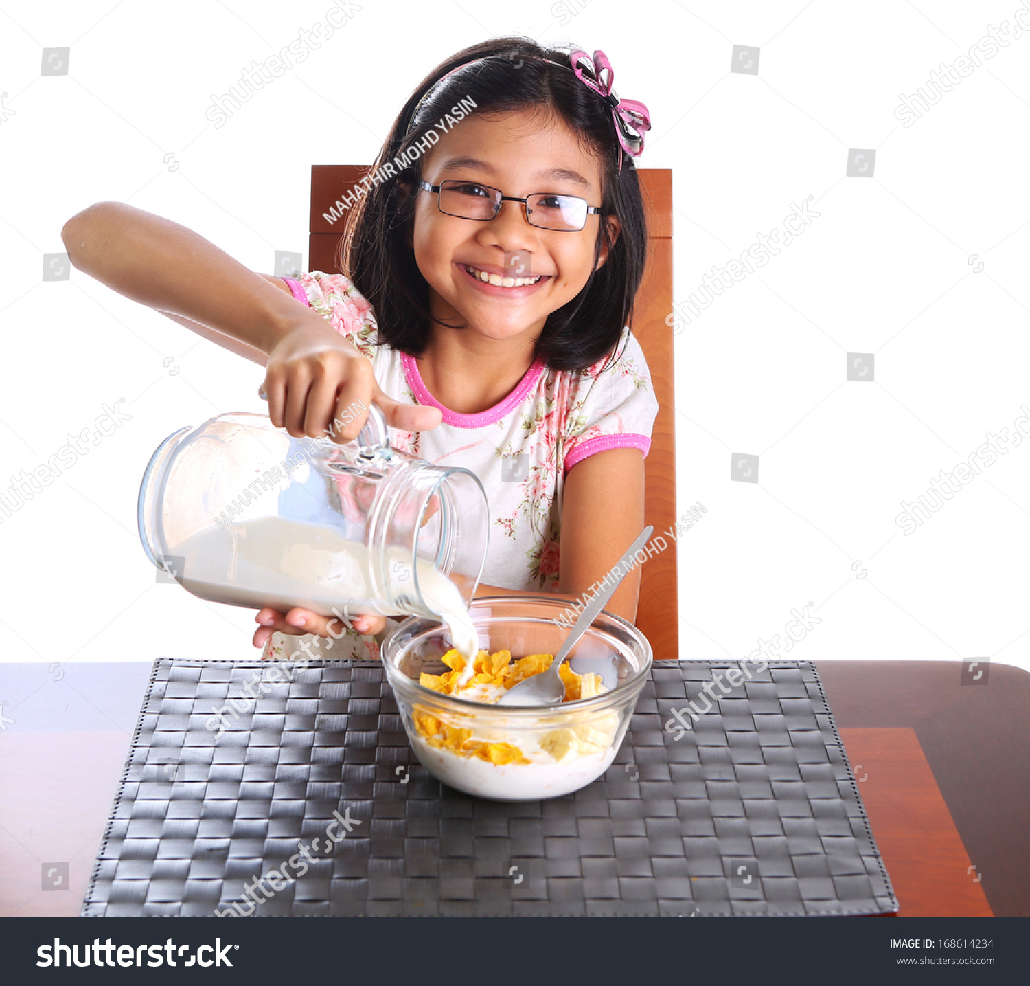 Young Asian Girl Pouring Milk Into A Bowl Of Cere