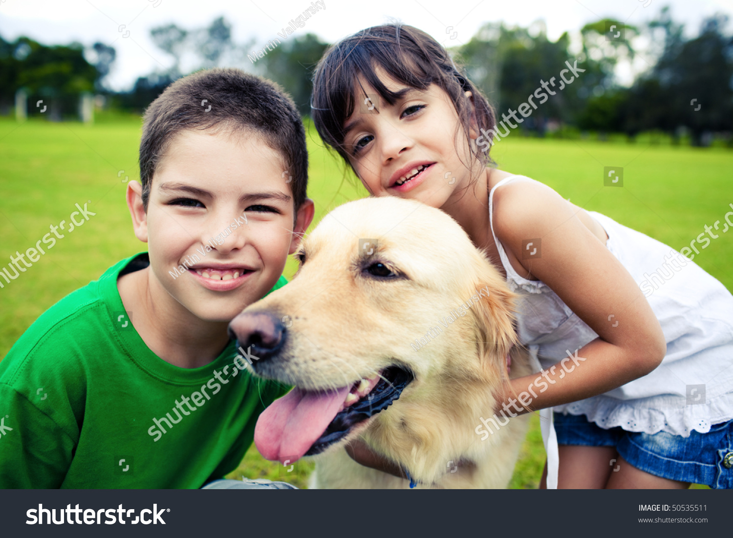 Young Boy And Girl Hugging A Golden Retriever Outdoors Stock Photo 