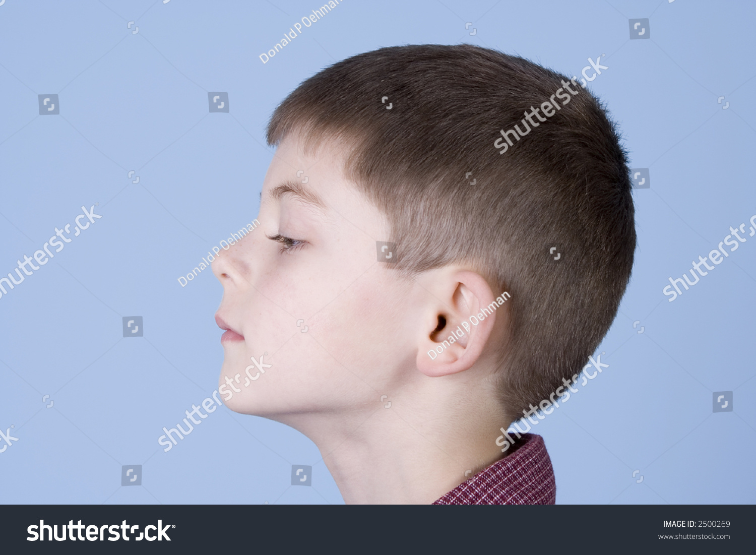 Young Boy Head Shot From The Side Profile Not Smiling On A Blue