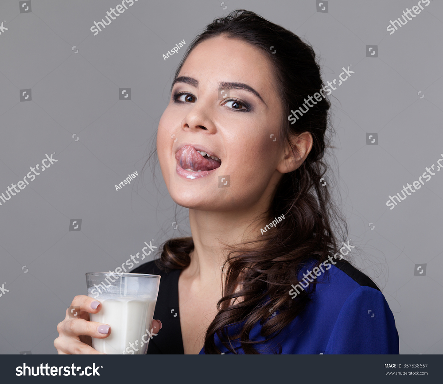 Young Brunette In A Black And Blue Shirt Licking Milk From A Goblet
