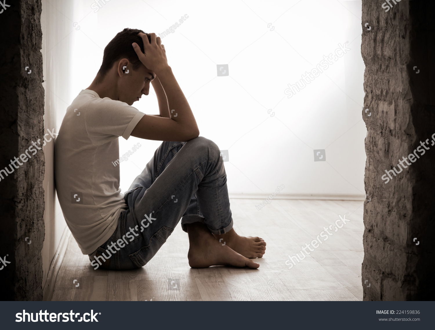 Young Man Sitting On A Floor With Hands On Head. Plenty Of Copy Space