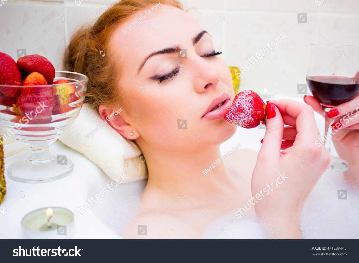 Young Woman Eating Strawberry While Lying In The Bath With Foam And