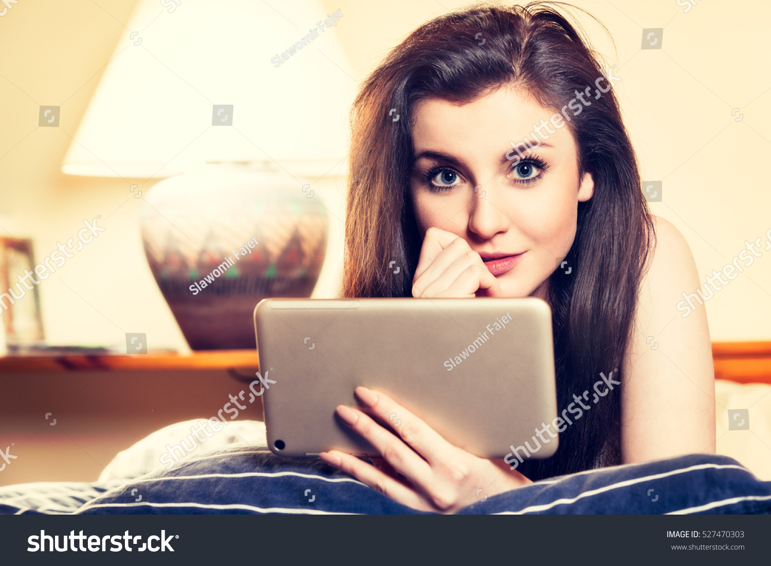 Young woman lying on the bed and using tablet Technology education internet concept Toned image Young woman lying on the bed and using tablet Technology education internet concept Toned image