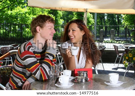 young couple drinking coffee in open-air cafe