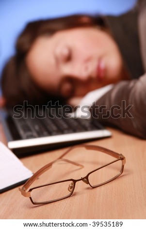 young businesswoman fell asleep at work (glasses in focus)