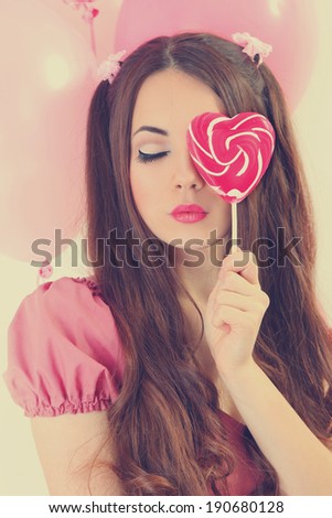 cute young woman dressed as a doll holding lollipop