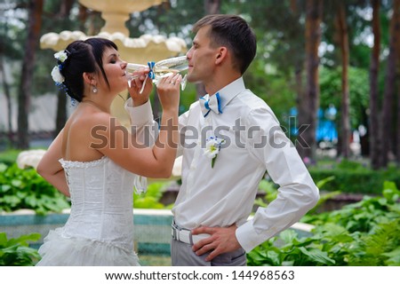 bride and groom drinking champagne on the background of the fountain