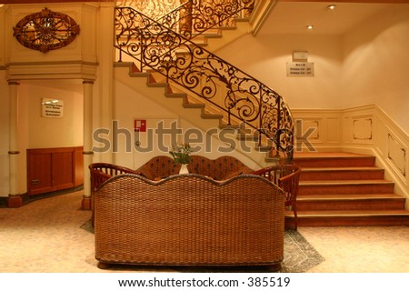 vintage stairway in old hotel building with rattan sofa in lobby area