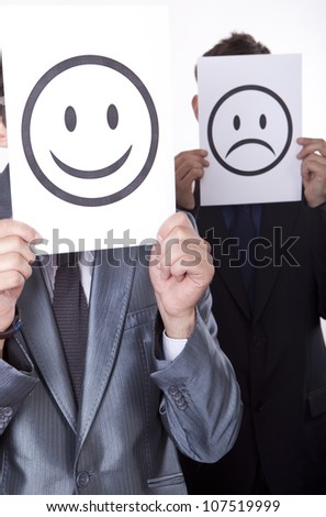 Two young men holding smiley and sad smiley face.