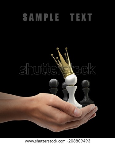 Man hand holding object ( Pawn in a golden crown ) isolated on black background. High resolution