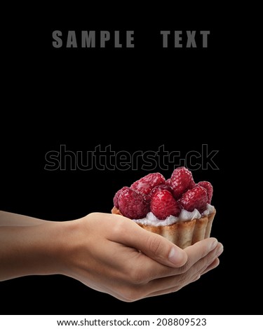 Man hand holding object ( tiny tart with raspberry on top ) isolated on black background. High resolution