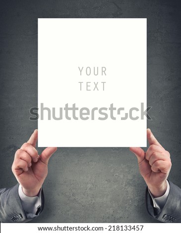 Hands holding big blank paper on grunge background