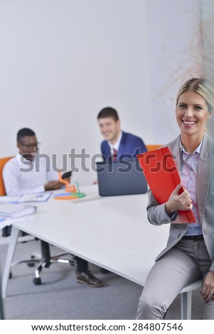 Young beautiful successful business woman working in the office and in the background of her colleagues