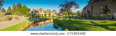 Pretty traditional cottages bathed in warm early morning sunlight in the idyllic village of Lower Slaughter, UK. Stitched panoramic image.