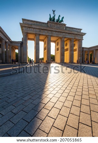 Dramatic sunlit Brandenburg Gate (1788) inspired by Greek architecture, built as a symbol of peace and nationalism, now an emblem of reunification.