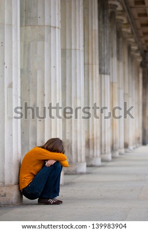 Sad girl is sitting near columns