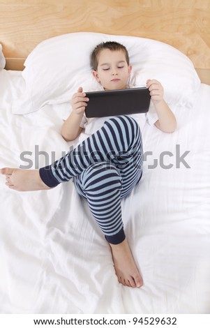 Elementary school boy reading his tablet before he goes to bed