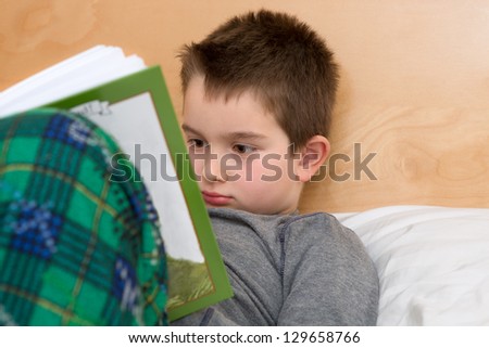 Bed Time Reading in pajamas; eight years old kid reading his book before sleep time.