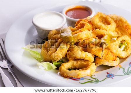 Deep fried breaded calamaris served with white and red sauce and topped with hot pepper pickles