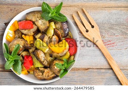 Grilled and Sauteed vegetables including eggplants, zucchini, red and yellow sweet peppers, garlic, garnished with mint and ready to served on rustic wooden table