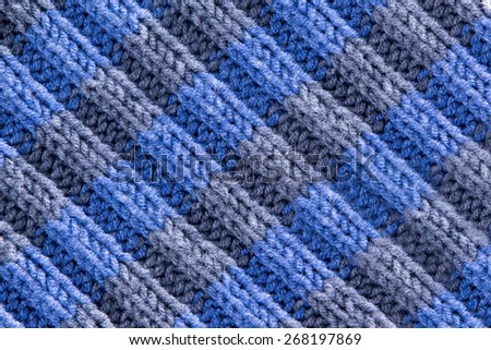 Background texture of handmade crochet work in blue and grey with a wavy repeating ridged pattern with weave, yarn and fiber detail and diagonal ridged lines, full frame close up from above