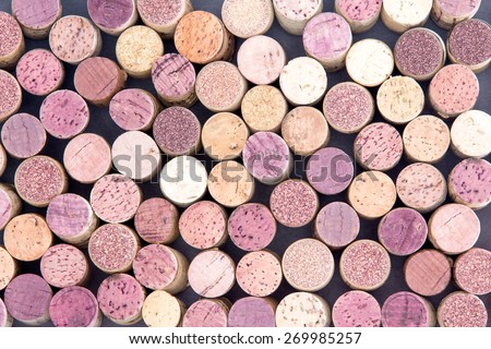 Old wine corks arranged in a background pattern viewed from above with both red and white wine represented in a random scatter, full frame
